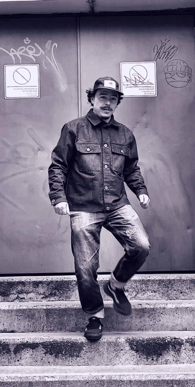 Sebastian A. de Blue Repair, con chaqueta y jean selvedge, bajando unas escaleras en Medellín